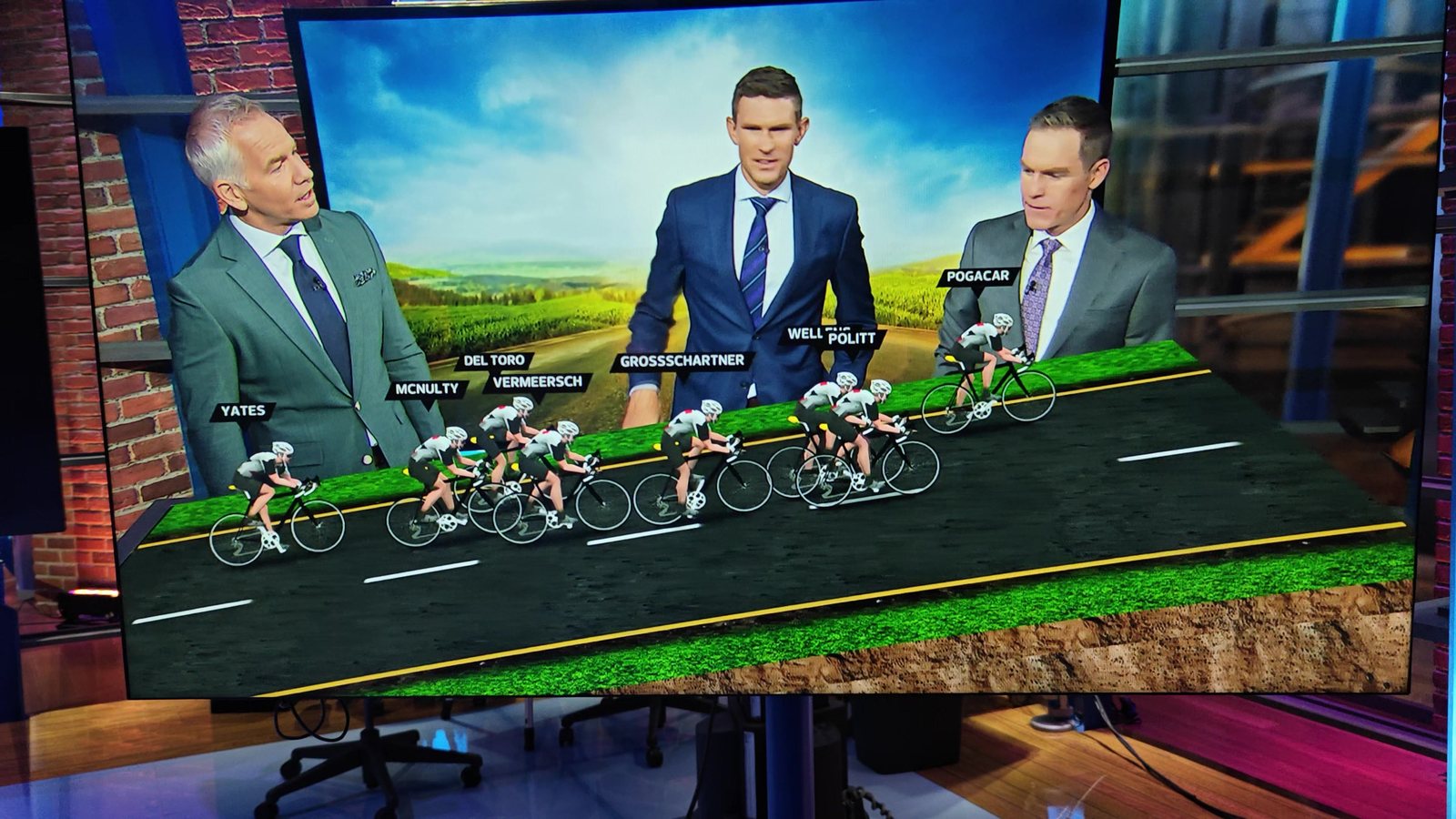 NBC Sports analysts standing inside a Sandbox AR scene — a 3D peloton of UAE Team Emirates riders on a virtual road