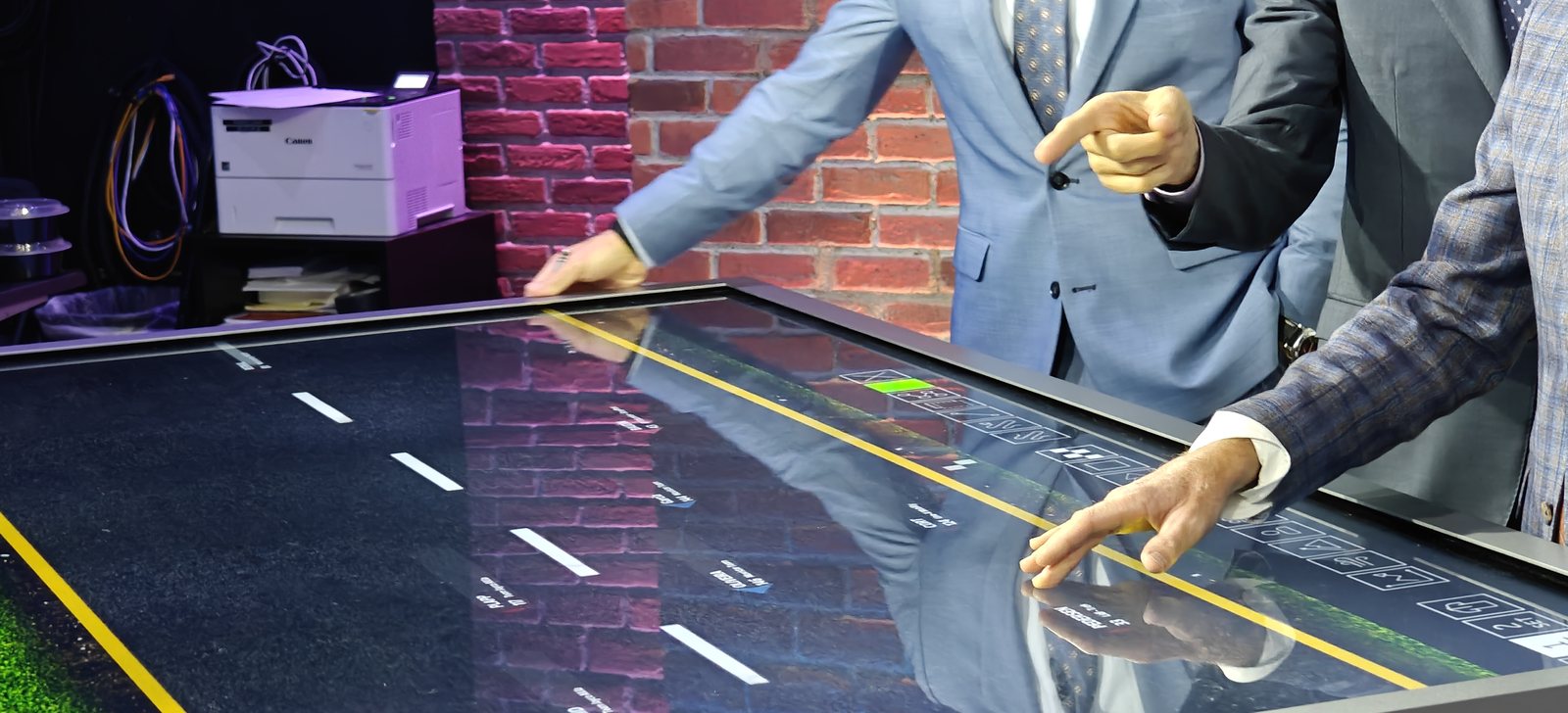 An analyst's hand reaching into the AR to move a rider on the virtual road surface